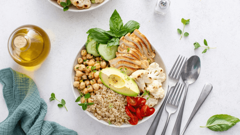 Healthy lunch bowl with high protein food, sliced grilled chicken, chickpeas and quinoa, and fresh vegetables